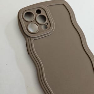 May include: A brown phone case with a wavy design and a raised camera lens cutout.