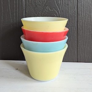 Puede incluir: Conjunto de cuatro boles de mezcla vintage en amarillo, rojo, azul y blanco. Los boles están apilados uno encima del otro.