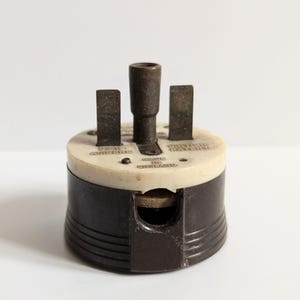 May include: A vintage brown and white electrical plug with three prongs and a round base. The plug is labelled "6 AMP FUSE" and "MADE IN ENGLAND".