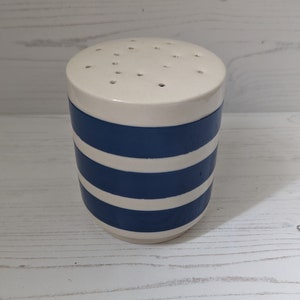 May include: A ceramic salt shaker with a white top and a cylindrical body. The body is decorated with alternating horizontal stripes of navy blue and white. The top has several small holes for dispensing salt.