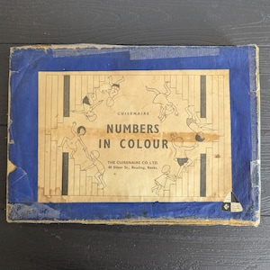 Può includere: Gioco educativo vintage intitolato "Numbers in Colour" di Cuisenaire. La copertina presenta uno sfondo beige con bambini che salgono le scale e il titolo è in grassetto. La copertina è incorniciata da un bordo blu.