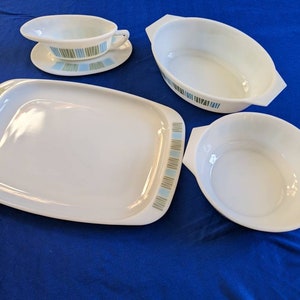 May include: A set of four white ceramic dishes with a blue and green striped pattern. The dishes include a large rectangular serving dish, a small oval dish, a small round dish, and a gravy boat with a matching saucer.