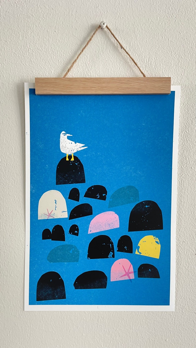 May include: A blue and white print of a seagull perched on a rock with a starfish in the foreground. The print features a variety of black, white, pink, and yellow rocks.