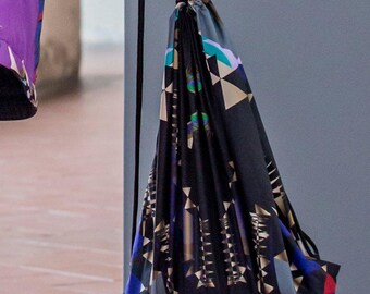 May include: A black drawstring bag with a geometric pattern in shades of blue, green, gold, and red. The bag has a black drawstring and the word "COLORAT" printed on the front.
