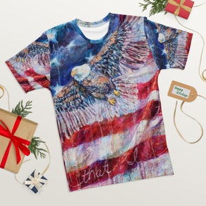 May include: A blue, red, and white t-shirt with a painting of an eagle flying over an American flag. The text "that I" is written on the bottom of the shirt.