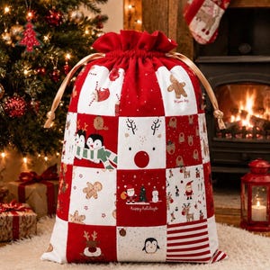 May include: A large red and white drawstring gift sack featuring a patchwork design with various Christmas-themed illustrations including gingerbread men, reindeer, penguins, Santa Claus, snowmen, and the text "happy holidays" in cursive script.
