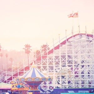 a carnival with a ferris wheel and a flag on top of it