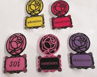 May include: Nine round rose-shaped paper cutouts with black outlines and different colored backgrounds. Each cutout has a small rectangular frame with a French word printed in black. The words are: choix, raison, amour, adoration, conviction, soi, conscience, révolution.