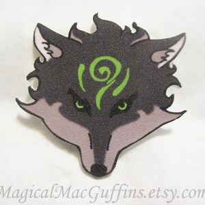 May include: A black and green wolf head with a green swirl design on its forehead. The wolf's eyes are green and the fur is textured.
