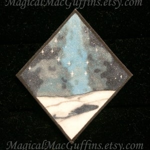 May include: Diamond-shaped patch with a snowy landscape and a blue starry sky. The sky is a dark blue with white stars and a light blue aurora borealis. The snow is white with a dark shadow in the foreground.