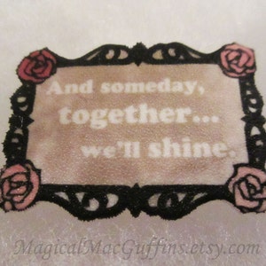 May include: A black and white decorative frame with a pink and white floral design. The frame has the text "And someday, together... we'll shine."