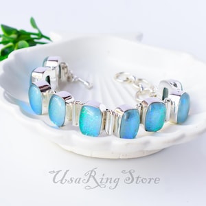 以下が含まれることがあります： チェーン留め具と、シルバーにセットされた複数のブルーオパールストーンが付いたシルバーブレスレット