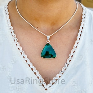 Peut inclure: Un collier en chaîne argent avec un pendentif triangulaire orné d'une pierre de malachite verte.