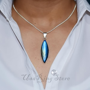 May include: A silver chain necklace with a pendant featuring a blue and green labradorite gemstone in a teardrop shape.