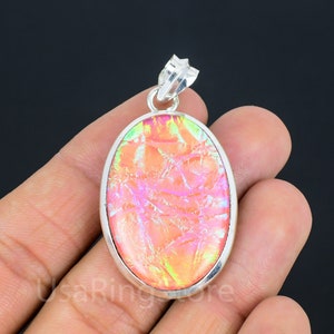 May include: Silver pendant with a large oval-shaped iridescent pink and green glass stone.