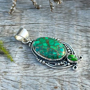 Close-up of a Handmade Green Copper Turquoise Pendant featuring an oval turquoise stone set in solid 925 Sterling Silver. Includes two turquoise stones for a unique look. Ideal anniversary gift.