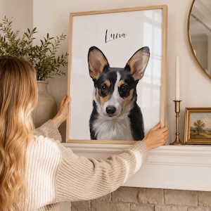 May include: A framed portrait of a Corgi dog with black, white, and brown fur. The dog's name, "Luna," is written above the image in a cursive font. The frame is light-colored wood.