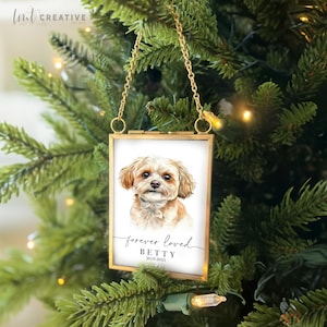 May include: A gold-framed glass ornament with a white background featuring a watercolor painting of a small, light brown dog. The text "forever loved BETTY 2018-2023" is printed below the dog.