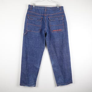 May include: Blue denim carpenter jeans with orange stitching and a small logo on the back pocket.