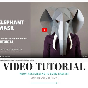 May include: A grey geometric paper elephant mask with white tusks. The video thumbnail features the text ELEPHANT MASK TUTORIAL BY SMAGA PAPERWOOD. Below the video, the text reads VIDEO TUTORIAL NOW ASSEMBLING IS EVEN EASIER! LINK IN DESCRIPTION.