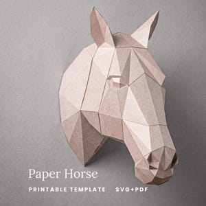 Op de afbeelding: Een lichtbruine papieren paardenhoofdsculptuur met een geometrisch, gefacetteerd ontwerp. De tekst smagapaperwood, Paper Horse, PRINTABLE TEMPLATE en SVG+PDF is zichtbaar. De sculptuur is opgebouwd uit meerdere hoekige papieren panelen.