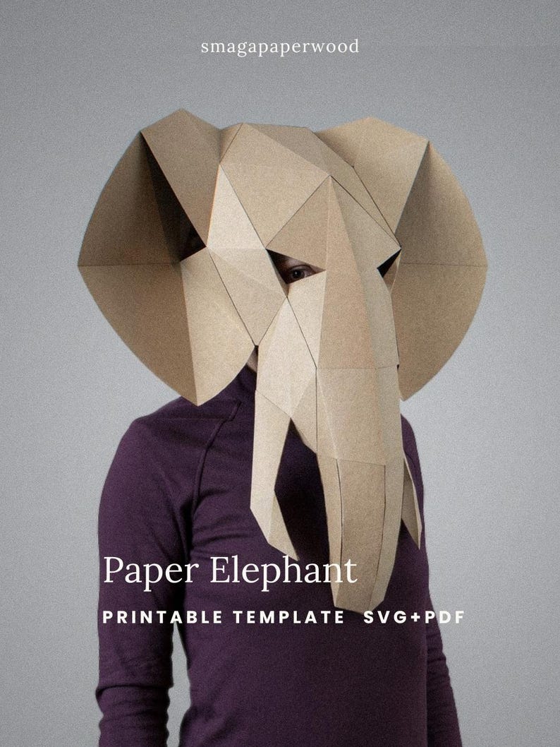 May include: A geometric elephant mask constructed from tan paper, featuring large ears and a trunk. The text smagapaperwood, Paper Elephant, and PRINTABLE TEMPLATE SVG+PDF are visible on the image. The mask is worn over a dark purple shirt.
