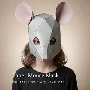 Op de afbeelding: Een geometrisch papieren muismasker met een lichtgrijze, gefacetteerde structuur, grote, afgeronde lichtroze oren en een kleine roze neus. Het masker heeft ronde oogopeningen en is voorzien van de tekst Paper Mouse Mask PRINTABLE TEMPLATE SVG+PDF.