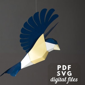Puede incluir: Un móvil de papel de pájaro azul y dorado con un diseño geométrico. El pájaro está en vuelo con las alas extendidas. El texto "PDF SVG digital files" está en la esquina inferior derecha de la imagen.