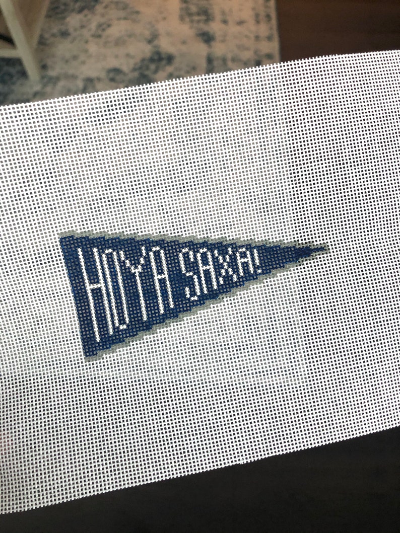 May include: A white canvas with a blue pennant that says "HOYA SAXA!" in white lettering.