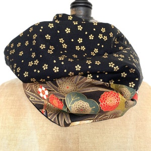 Peut inclure: Un snood à motifs floraux noirs et dorés. La couche supérieure présente de petites fleurs dorées sur fond noir. La couche inférieure présente un motif floral avec des accents rouges, blancs et verts sur fond sombre.