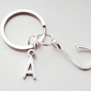 May include: Silver keyring with a letter A charm, a small silver ring, and a silver fish hook charm.
