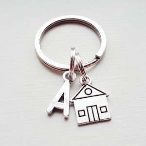 May include: Silver keyring with a house charm and a letter A charm.
