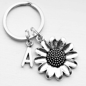 May include: Silver keyring with a sunflower charm and a letter A charm.
