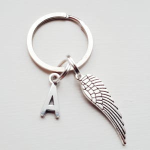 May include: Silver keychain with a letter A charm and a silver angel wing charm.