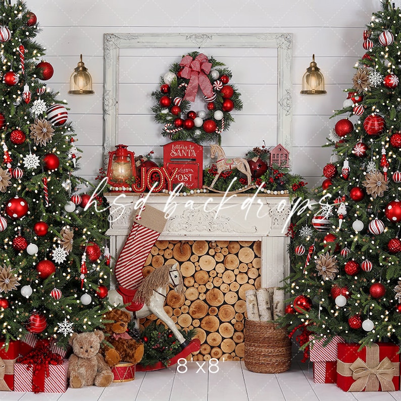 May include: A Christmas-themed backdrop with two decorated trees, red baubles, and fairy lights. A fireplace with a log-filled hearth is central, decorated with a stocking, rocking horse, and a wreath. The backdrop includes the text "hsd backdrops" and "8'x8'".