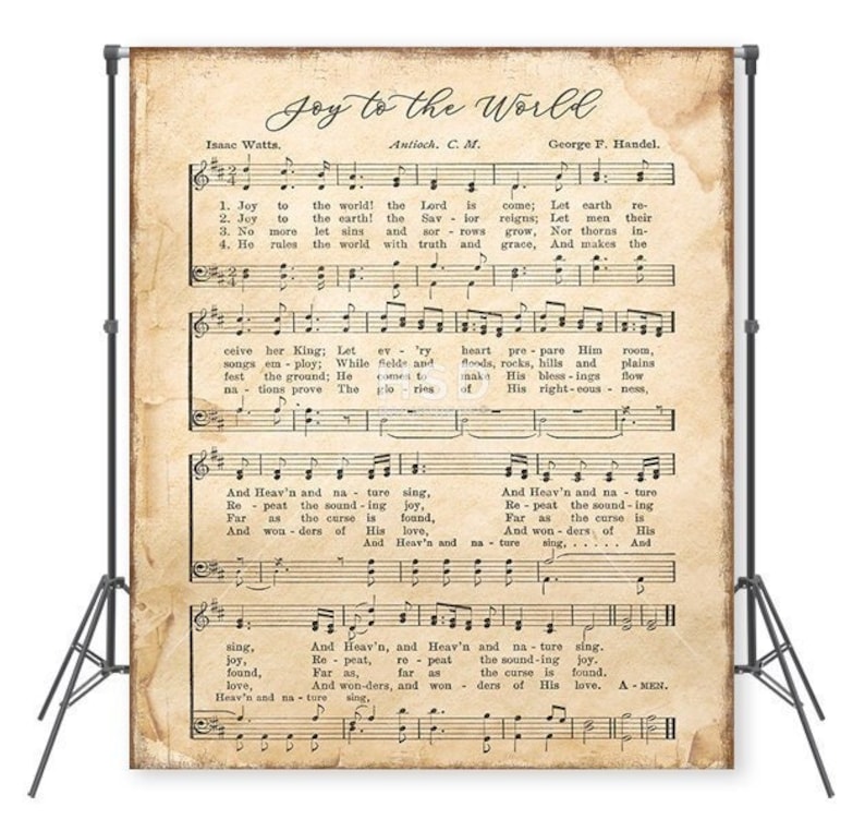 May include: A vintage-style musical score backdrop featuring the hymn "Joy to the World." The sheet music is printed on aged paper, with the title and lyrics clearly visible. The backdrop is supported by a black stand.