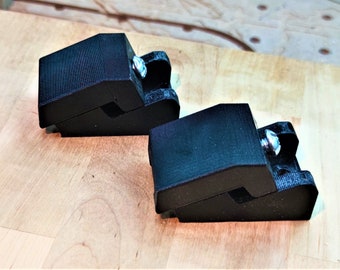 Puede incluir: Dos abrazaderas de plástico negro con un tornillo plateado en cada una. Las abrazaderas están diseñadas para sujetar objetos en su lugar.