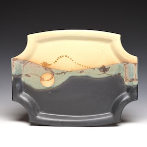 May include: A rectangular ceramic tray with curved edges, featuring a tri-color glaze. The top section is cream, the middle is a muted sage green with a dotted arc and circular motif, and the bottom section is a solid matte black finish.