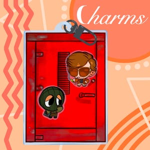 May include: A red door charm with two cartoon character stickers and the word "Charms" in white script. One sticker depicts a man in sunglasses, and the other shows a character in a green mask. The charm has a silver clasp.