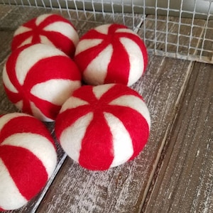 K&ouml;nnte beinhalten: F&uuml;nf rote und wei&szlig;e Pfefferminzbonbon-f&ouml;rmige Ornamente aus Filz.