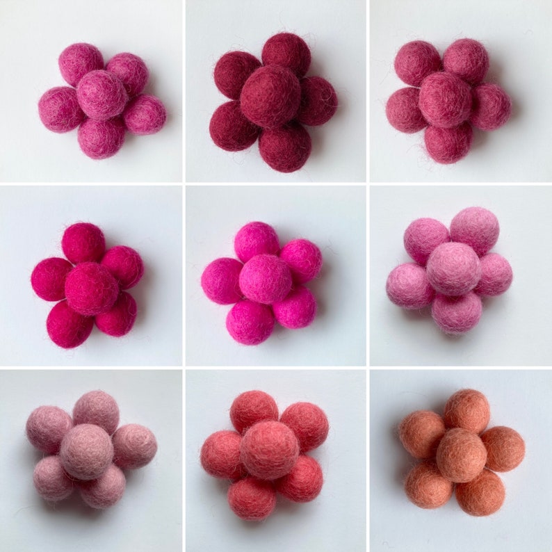 May include: Nine felt balls arranged in a flower shape. The balls are in three different shades of pink, from light to dark.