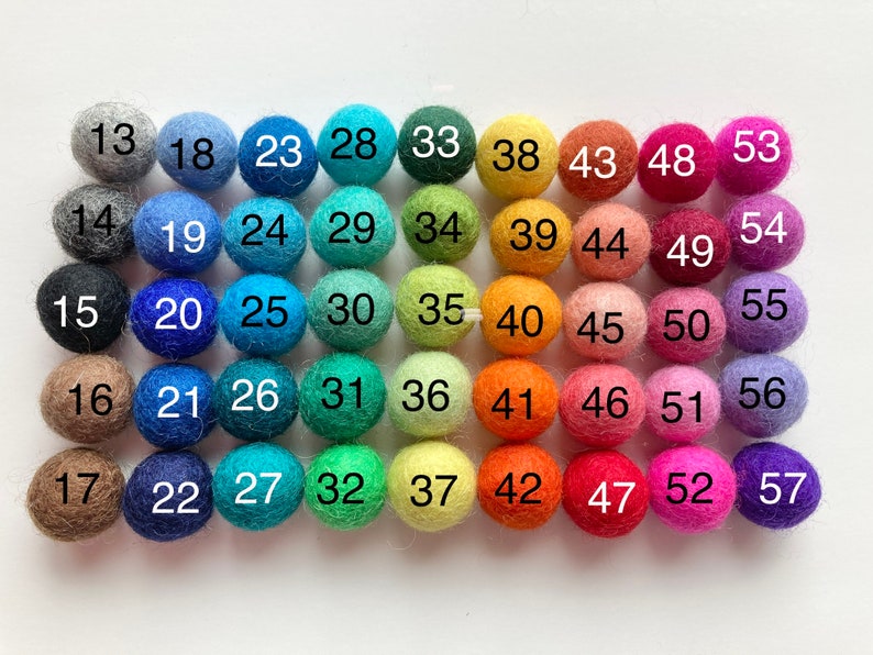 May include: A color chart of 57 felt balls, arranged in rows of 9, with numbers 13 through 57 printed on each ball. The balls are in a variety of colors, including gray, blue, green, yellow, orange, red, pink, purple, and brown.