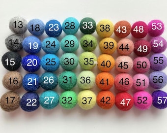 May include: A color chart of 57 felt balls, arranged in rows of 9, with numbers 13 through 57 printed on each ball. The balls are arranged in a rainbow color pattern, starting with gray and ending with purple.