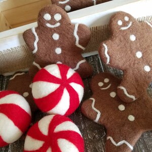 K&ouml;nnte beinhalten: Eine Sammlung von Weihnachtsornamenten aus Filz, darunter Lebkuchenm&auml;nner und Pfefferminzbonbons. Die Ornamente sind braun, wei&szlig; und rot.