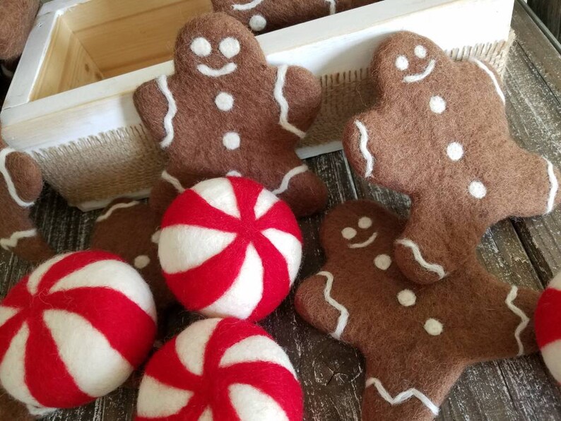 K&ouml;nnte beinhalten: Eine Sammlung von Weihnachtsornamenten aus Filz, darunter Lebkuchenm&auml;nner und Pfefferminzbonbons. Die Ornamente sind braun, wei&szlig; und rot.