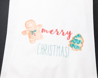 May include: White paper gift bag with a gingerbread man and a Christmas tree illustration. The bag has the text "merry christmas!" printed on it.