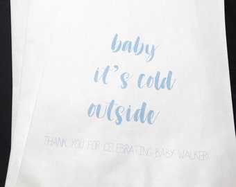 May include: White paper gift bags with blue text that reads "baby it's cold outside" and "Thank you for celebrating baby Walker!"