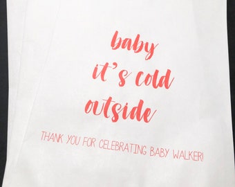 May include: White paper gift bags with red text that reads "baby it's cold outside" and "Thank you for celebrating Baby Walker!"