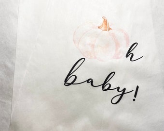 May include: White paper gift bag with a watercolor pumpkin and the text "oh baby!" printed on it.