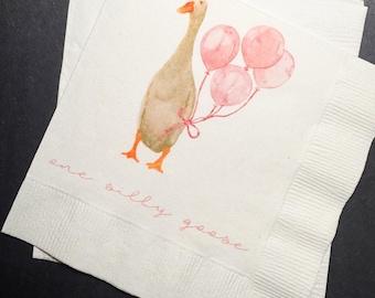 May include: White paper napkins with a watercolor illustration of a goose holding pink balloons. The goose is tan with orange feet and beak. The text "one silly goose" is written in pink script.